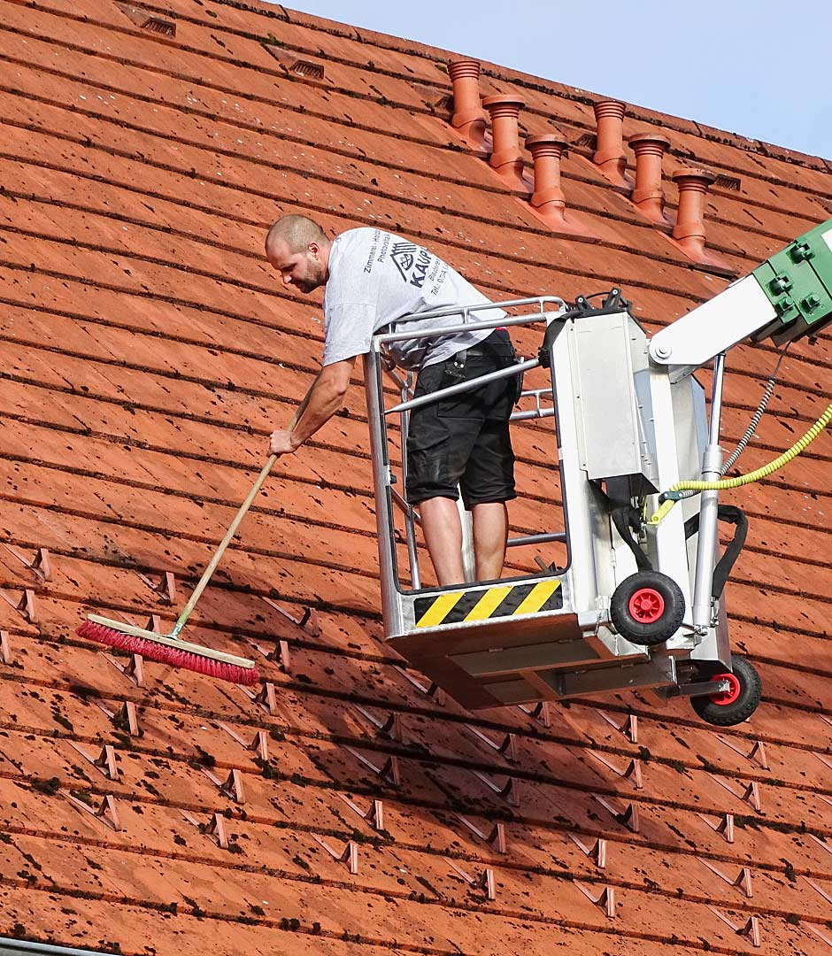 Ein Mitarbeiter der Zimmerei Kaupp beim reinigen eines Daches im Zuge einer Dachwartung